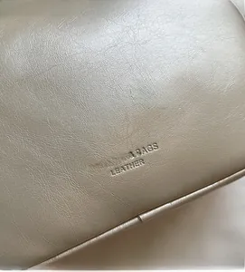 Close-up of champagne gold wrinkled leather texture with Fashion & Bags embossed logo