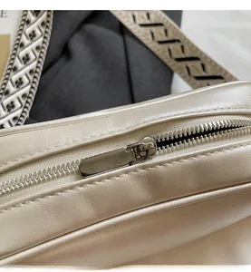 Close-up of silver zipper on beige PU leather bag with geometric patterned strap