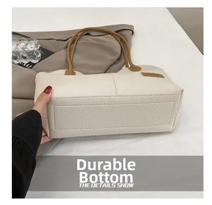 Detail view of the wear-resistant reinforced bottom of this cream faux leather handbag