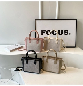 Close-up of four woven tote bags in pink, white, black and khaki on a minimalist display
