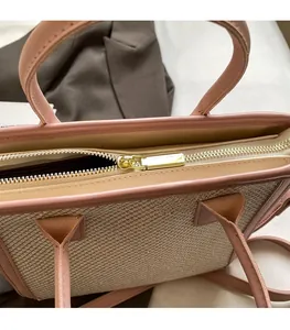 Detail of golden metal zipper on woven tote bag with pink leather trim and smooth closure