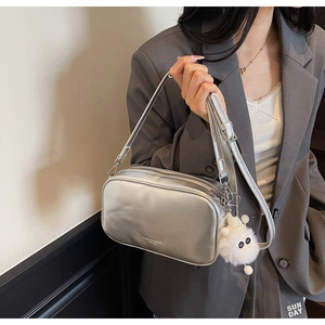 Detail of silver metallic square bag with wide strap and white plush monster charm