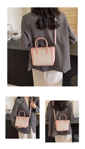 Detail view of woven pink and beige tote bag shown on model with adjustable strap