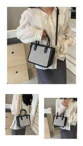 Detail of woven black and white tote bag with leather straps and gold-toned hardware
