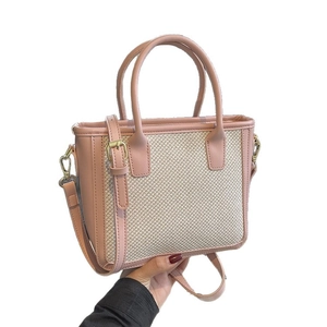 Pink leather and woven straw tote bag with dual handles and adjustable shoulder strap