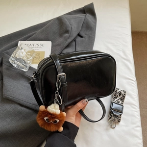 Fashion black leather crossbody bag with geometric wide strap and cute monster pendant
