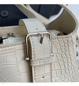 Detail of white crocodile-embossed leather texture with silver buckles and stud accents