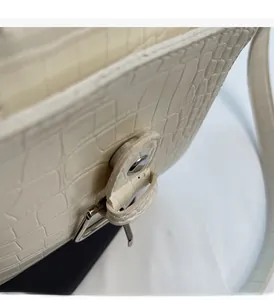 Detailed macro of white crocodile embossed leather and polished silver metal buckle
