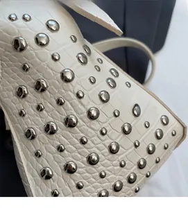 Detail of white crocodile embossed leather bag with silver punk style metal rivets