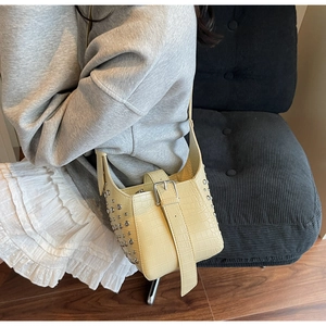 Detailed view of cream crocodile pattern bucket bag with silver studs and metal buckle