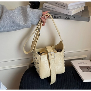 Detail of beige crocodile pattern bucket bag with silver rivets and buckle straps