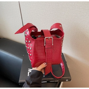 Detail of red crocodile texture handbag with silver rivets and wide adjustable strap