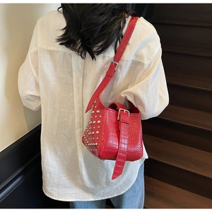 Detail of red crocodile textured bucket bag with silver rivets and adjustable buckle strap