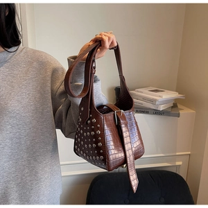 Close-up of dark brown crocodile pattern bucket bag featuring silver rivets on the side