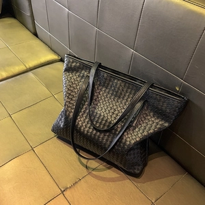 Minimalistische schwarze gewebte Leder-Shopper-Tasche mit Doppelgriffen auf einem Sofa