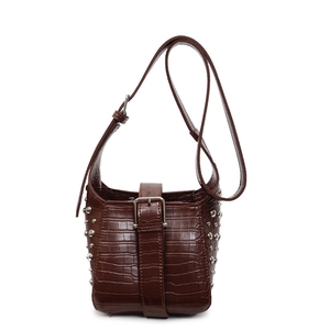 Detailed view of dark brown crocodile-embossed bucket bag with silver rivet studs