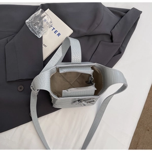 Detail view of light blue crocodile texture bucket bag with zipper and metal lock