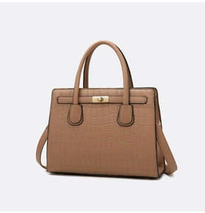 Detail of a brown crocodile pattern handbag with golden buckle and adjustable strap