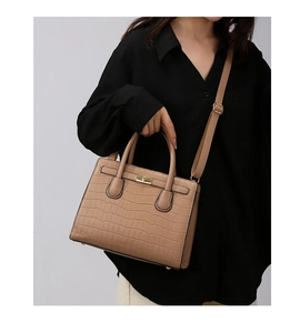 Detail of tan crocodile pattern handbag featuring gold twist lock and adjustable strap