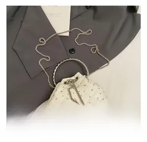 Detail of white quilted bucket bag with sparkling crystals and elegant pearl drawstring