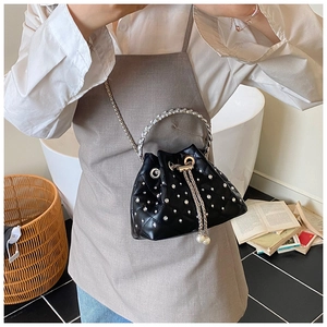 Close-up of black quilted bucket bag with rhinestone handle and pearl drawstring charms