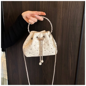 Detail of white quilted bucket bag with rhinestone ring handle and pearl drawstring