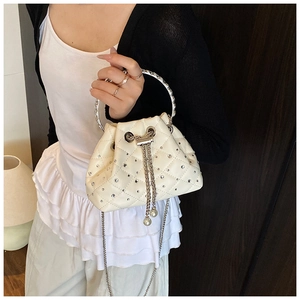 Detail of white quilted bucket bag with sparkling rhinestones and pearl drawstring charm