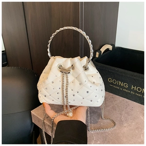 Close-up of white quilted bucket bag with crystal handle and pearl chain detail