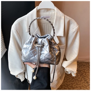 Detail of silver quilted bucket bag featuring stud accents and pearl chain drawstring