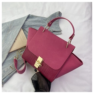 Close-up of fuchsia crocodile embossed leather bag with gold ring handle and metal lock