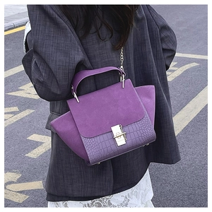 Detail of purple croc-effect bag with gold clasp shown on crossbody strap outdoor