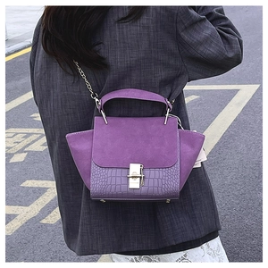 Detail of purple croc-embossed texture and suede flap on elegant crossbody bag