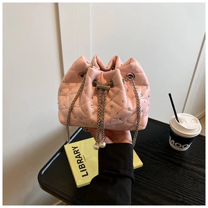 Detail of pink quilted bucket bag with rhinestones, metal chain, and pearl charms