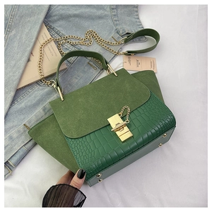 Detail of dark green crocodile texture bag with suede flap and gold chain strap