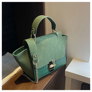 Detail of green crocodile embossed bag with gold metal twist lock and chain strap