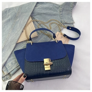 Detail of crocodile embossed leather texture and navy suede flap with gold metal lock