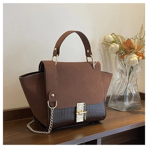 Detail of dual-material shoulder bag with crocodile pattern and golden metal buckle
