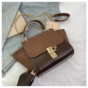 Detail of crocodile pattern leather bag with gold chain strap and textured flap closure