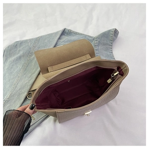 Detail of beige croc-embossed bag featuring a gold twist lock and burgundy inner lining