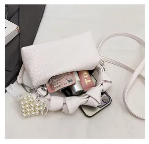 Detail of cream lychee leather handbag with knot handle and heart pearl charm