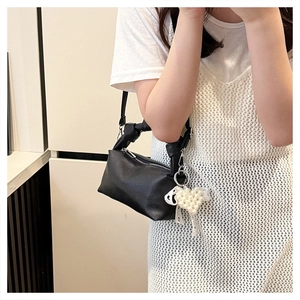 Detail of black lychee leather crossbody bag with pearl heart charm and lace bow decor