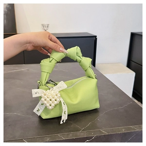 Detail of light green pebbled leather bag with knot handle and pearl heart charm