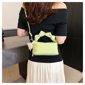Detail of lime green mini cloud bag with pearl bow charm and knotted handle