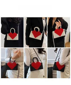 Detailed view of handmade beaded envelope bag with red heart pattern and pearl strap