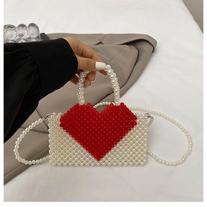 Detailed macro of handmade white beaded handbag with red heart and pearl shoulder strap