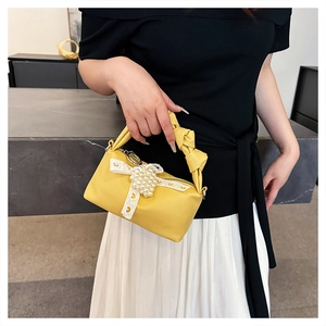 Detail of yellow textured handbag with white lace bow and faux pearls decoration