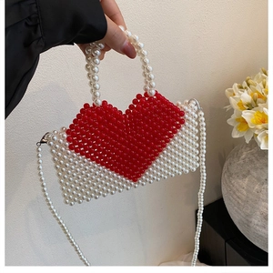 Detail of handmade beaded handbag with red heart pattern and pearl crossbody chain