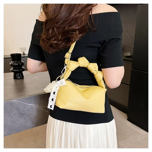 Macro view of bright yellow textured leather bag with pearl and lace heart pendant details