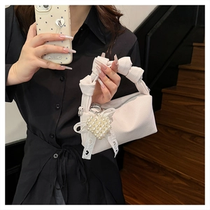 Detail of white leather cloud bag featuring pearl heart pendant and lace decoration