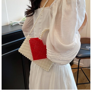 Detailed view of handmade pearl beaded handbag with large red heart pattern and dual straps